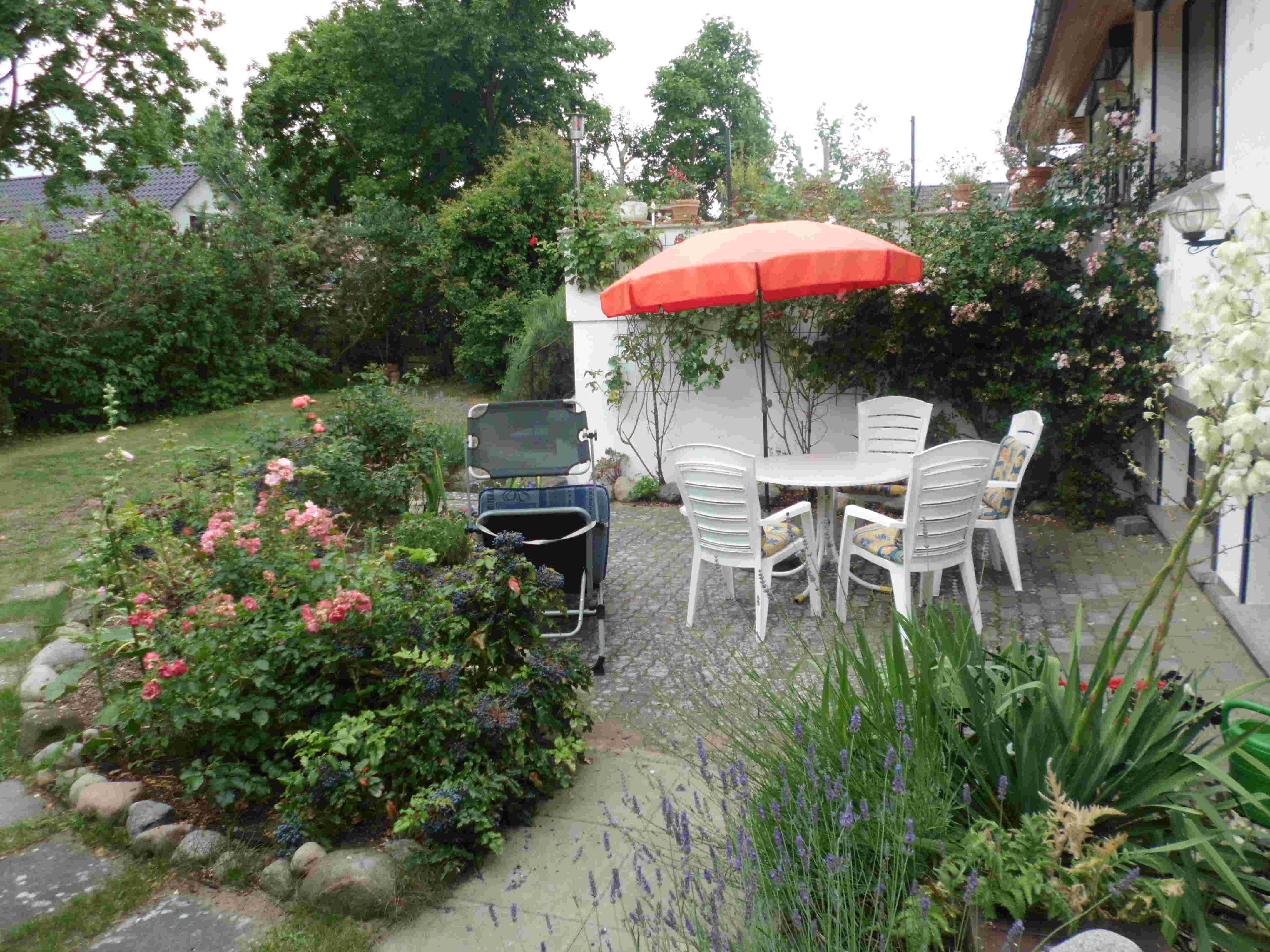 Von Rosen umwachsene Terrasse der Ferienwohnung mit Gartenmöbeln. Für den Radurlaub können die Fahrräder im Raum unterhalb der oberen Terrasse sicher abgestellt werden.